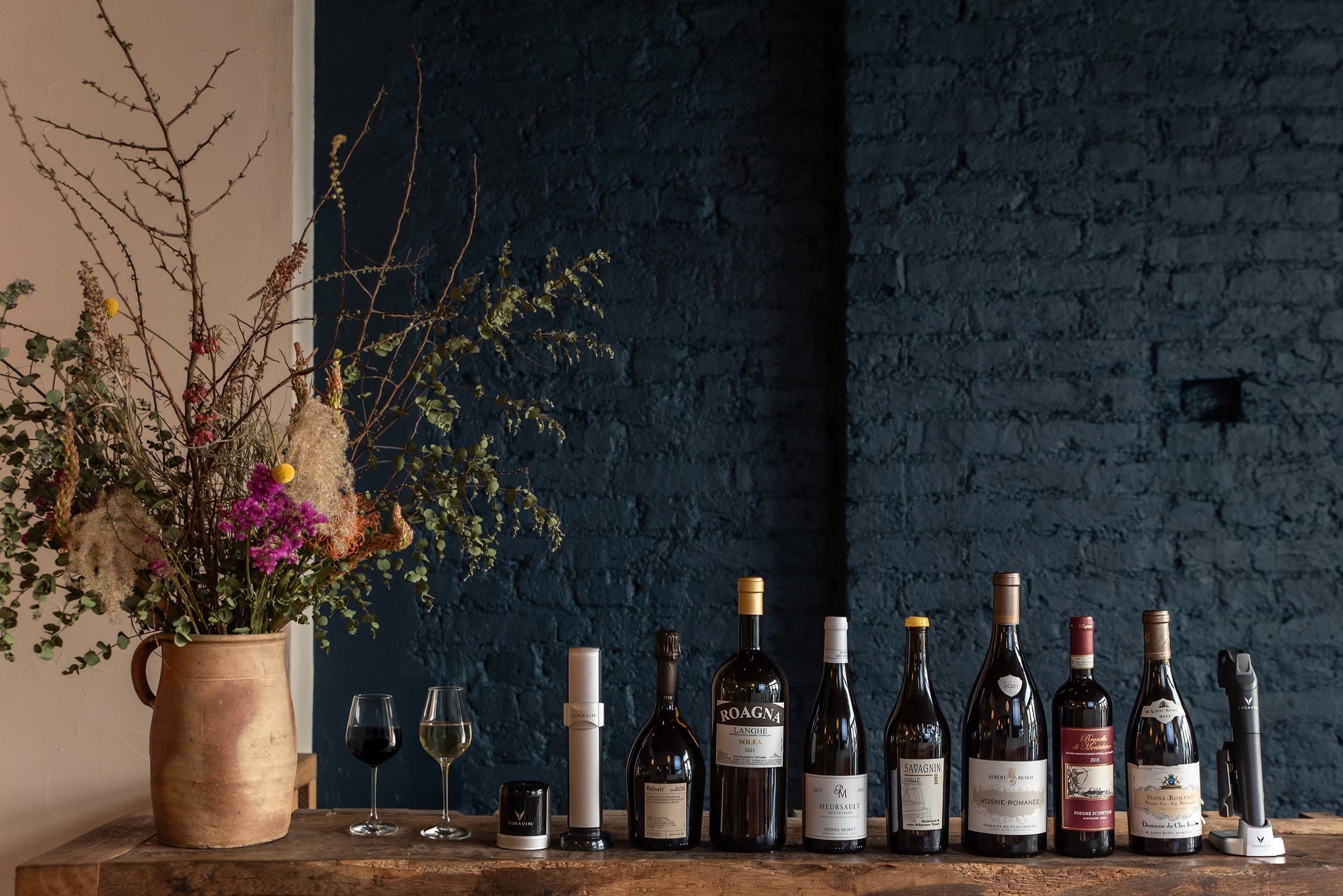 coravin sparkling and coravin pivot displayed with a line of wine bottles against a dark blue brick wall